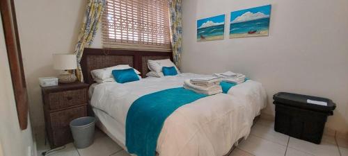 a bedroom with a bed with blue pillows at Santorini, Margate in Margate