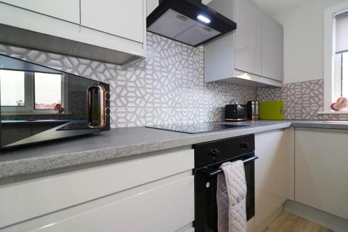 a kitchen with white cabinets and a microwave at Signature - Salisbury House in East Kilbride