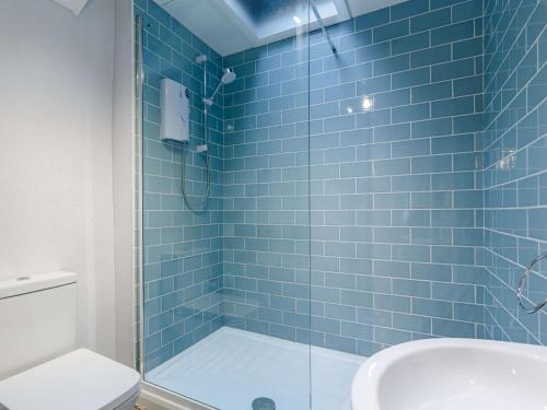 a blue tiled bathroom with a shower and a toilet at 3 Bed in Roseland 85494 in Ruan Lanihorne