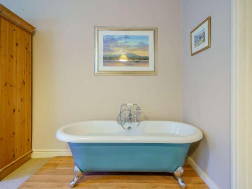 La salle de bains est pourvue d'une baignoire bleue et d'une photo murale. dans l'établissement 1 bed property in Keswick 86117, à Braithwaite