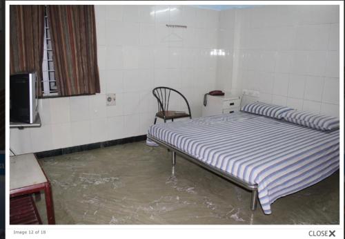 a room with a bed and a chair in it at Paradise Guest House in Chennai