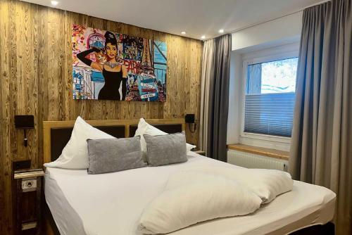 a bedroom with a white bed with a painting on the wall at Quality Hosts Arlberg - ALPtyrol Appartements in Sankt Anton am Arlberg
