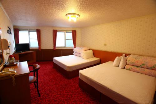 una camera d'albergo con 2 letti e una scrivania di Yeashow Villa a Fenchihu