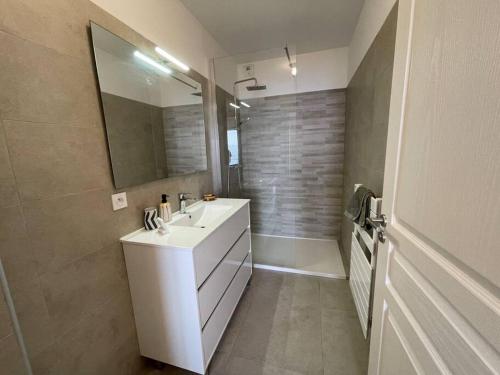 une salle de bain avec un lavabo blanc et un miroir dans l'établissement Appartement T3 face à la mer, à Ajaccio