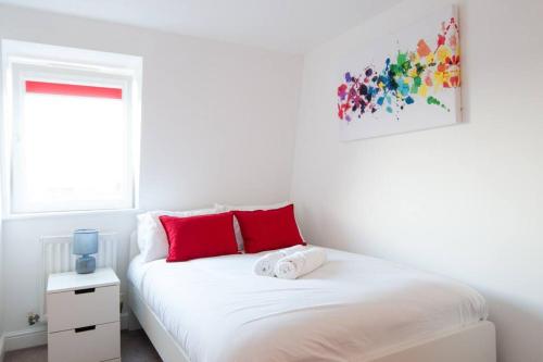 a white bedroom with a bed with red pillows at Caribou Suite-Bright & Spacious 2-Bed, Gated Parking, Close to City & Hospital in Burton upon Trent