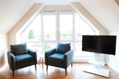 a living room with two chairs and a flat screen tv at Caribou Suite-Bright & Spacious 2-Bed, Gated Parking, Close to City & Hospital in Burton upon Trent