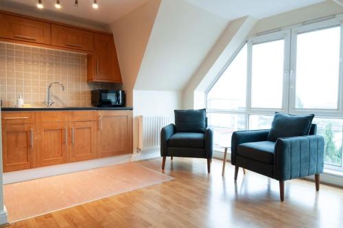 a kitchen with two chairs and a kitchen with windows at Caribou Suite-Bright & Spacious 2-Bed, Gated Parking, Close to City & Hospital in Burton upon Trent