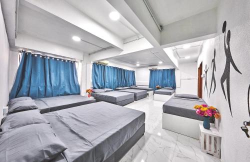 a bedroom with two beds and blue curtains at Penang Dream Banglo Sleeps 50 in Tanjung Bungah