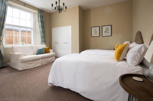 ein Schlafzimmer mit einem großen weißen Bett und einer Couch in der Unterkunft Willow Cottage in Cockburnspath