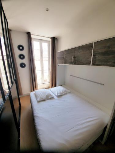 un lit blanc dans une chambre avec une fenêtre dans l'établissement L'ORATOIRE 2, à La Rochelle
