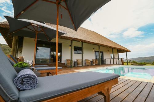 a house with an umbrella and a swimming pool at Barefoot Addo Elephant Lodge - Luxury Family Villa in Addo
