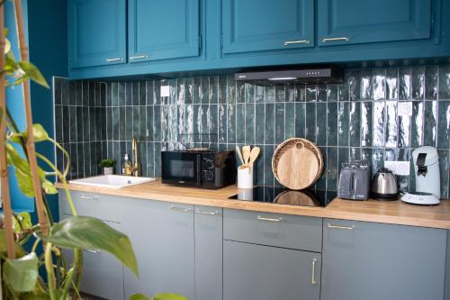 une cuisine avec des armoires bleues et un comptoir dans l'établissement Superbe Suite Bali – Écran cinéma – Clim – Béziers, à Béziers