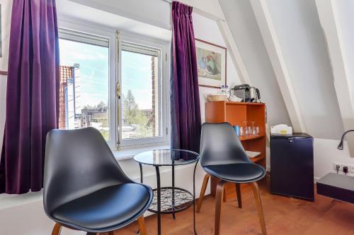 two chairs and a table in a room with a window at City-centre, Canal-house, luxurious , stylish bedroom, ensuite bathroom in Amsterdam