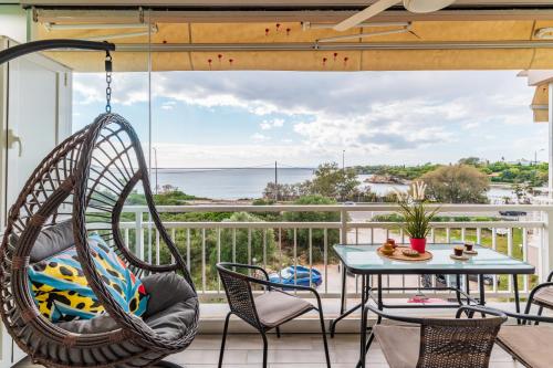 a porch with a swing and a table and chairs at Fantastic sea view one-bedroom apartment - Lagonissi in Lagonissi