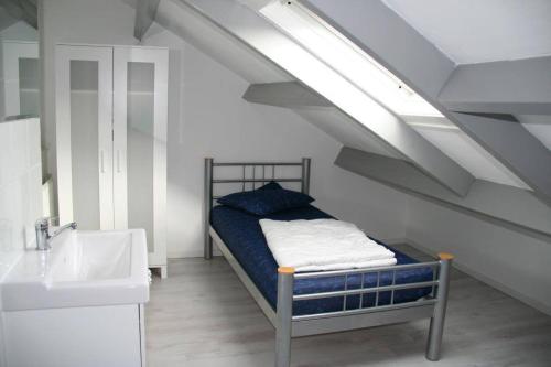 ein Schlafzimmer mit einem Bett und einem Waschbecken im Dachgeschoss in der Unterkunft Schorrebloem 21* in Nieuwvliet