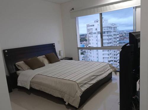 - une chambre avec un grand lit et une grande fenêtre dans l'établissement Lindo apartamento con excelente vista Bahía, à Carthagène des Indes