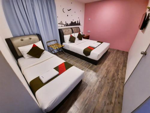 2 camas en una habitación pequeña con paredes rosas en Good2Stay Hostel en Melaka