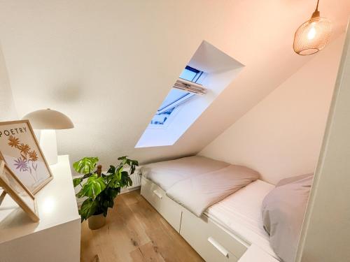 - une petite chambre mansardée avec un lit et une fenêtre dans l'établissement Modernes Apartment in Diepholz, à Diepholz