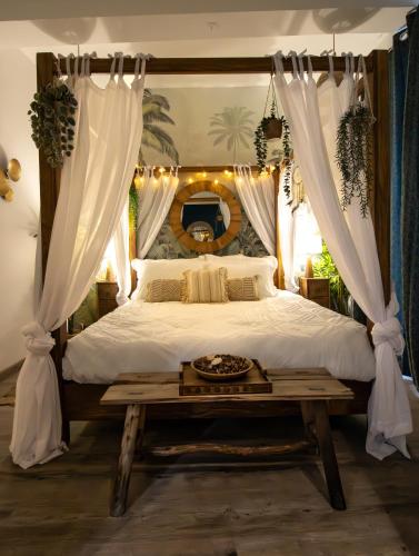 - une chambre avec un lit à baldaquin et une table dans l'établissement Superbe Suite Bali – Écran cinéma – Clim – Béziers, à Béziers