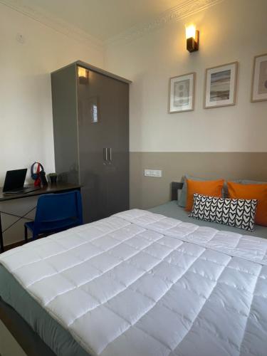 een groot wit bed in een kamer met een bureau bij Home Tales 275 by Tipiverse in Bangalore