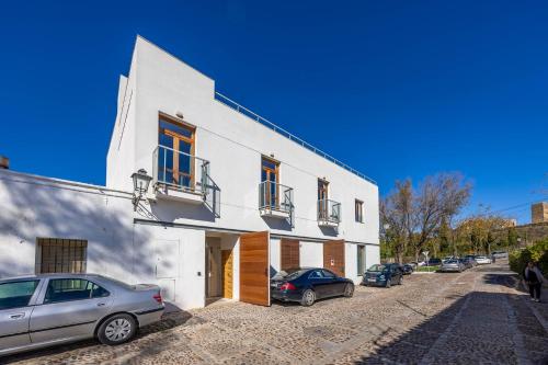 a white building with cars parked in front of it at Casa Xanadu Carmona - Stylish villa with rooftop terrace and stunning views of Parador in Carmona