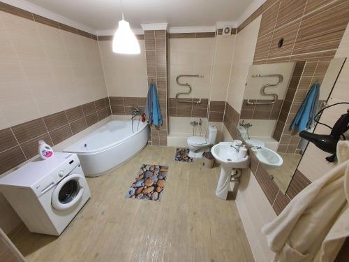 y baño con bañera, lavabo y lavadora. en 2-ух комнатная квартира Юнис Сити г.Актобе, en Aktobe