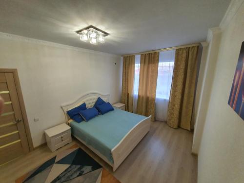 Un dormitorio con una cama con almohadas azules y una lámpara de araña. en 2-ух комнатная квартира Юнис Сити г.Актобе, en Aktobe