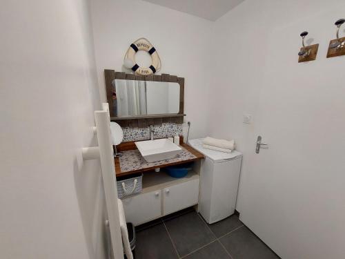 ein Badezimmer mit einem Waschbecken, einem Spiegel und einem WC in der Unterkunft VILLA HÉLIOS in Jard-sur-Mer
