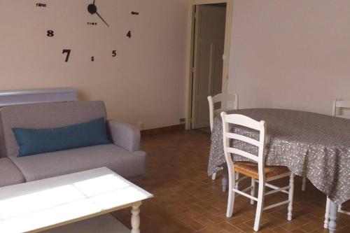 Maison village في Baudres: غرفة معيشة مع طاولة وأريكة وساعة