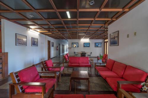 a waiting room with red chairs and a table at Praia Sol Hotel by Castelo Itaipava in Serra