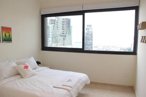 ein Schlafzimmer mit einem weißen Bett und einem großen Fenster in der Unterkunft Modern 3 Bed 3 Bath Apt w Sea View in Beirut