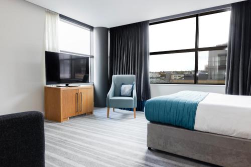 a hotel room with a bed and a tv and a chair at Crowne Plaza Newcastle - Stephenson Quarter, an IHG Hotel in Newcastle upon Tyne