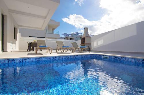 a swimming pool with chairs and a table on a house at Villa Genesis in Protaras