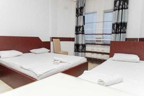 a room with two beds and a chair at Jusaj Hotel Glob in Peje