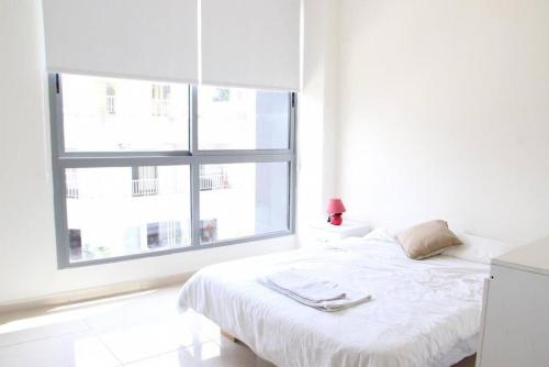 een witte slaapkamer met een bed en een raam bij Modern 3BR Apt next to Hotel Dieu in Beiroet