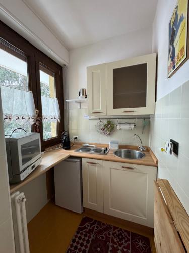 una pequeña cocina con fregadero y microondas en Gina's Home - Appartamento nel cuore di Bardonecchia en Bardonecchia