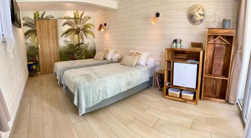 a bedroom with two beds and a flat screen tv at La Case O zoizos in Saint-Joseph