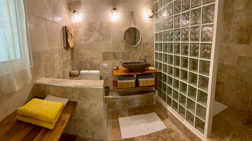 a bathroom with a tub and a sink with a yellow towel at La Case O zoizos in Saint-Joseph