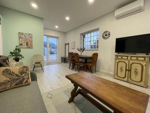 uma sala de estar com uma mesa e uma televisão de ecrã plano em Porto Area, Poolside Sunsets of Vila Boa 