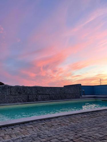 a swimming pool with a sunset in the background at Porto Area, Poolside Sunsets of Vila Boa in Vilarinho