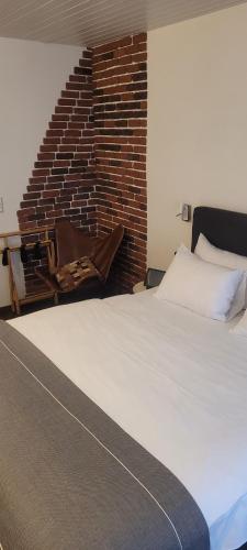 1 dormitorio con cama blanca y pared de ladrillo en Kreuzblume Hotel & Weinstube en Friburgo de Brisgovia