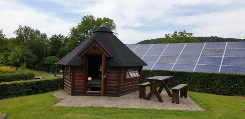 une petite maison avec une table et des panneaux solaires dans l'établissement Camping Officiel Wollefsschlucht Echternach, à Echternach