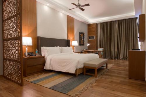 een slaapkamer met een bed, een tafel en een stoel bij The Westin Pushkar Resort & Spa in Pushkar