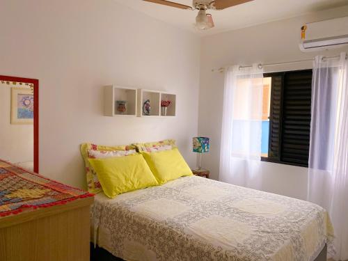 a bedroom with a bed with yellow pillows and a window at Residencial Privilegio in Florianópolis