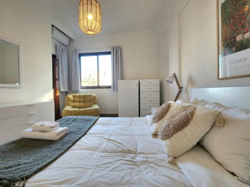 ein Schlafzimmer mit einem großen weißen Bett und einem Stuhl in der Unterkunft Chill 2Br haven Gemmayze in Beirut