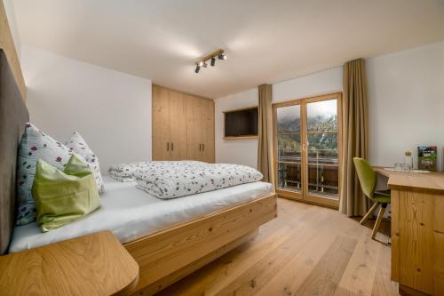 een slaapkamer met een bed, een bureau en een raam bij Pardellerhof Appartment Runcada in Luson