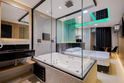 uma casa de banho com banheira e uma cama num quarto em Drops Express Motel Curitiba em Curitiba