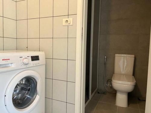 uma casa de banho com uma máquina de lavar roupa e um WC em Pleasant 1BR apt with green views - Jamhour em Rujūm