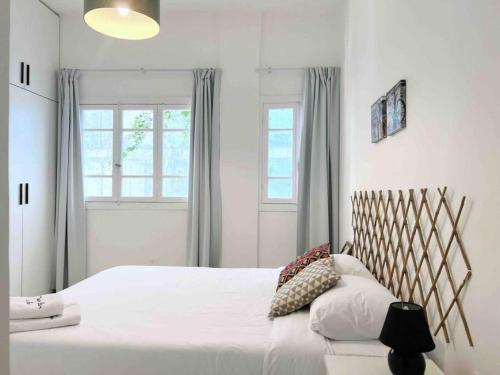 - une chambre dotée d'un grand lit avec des draps blancs et une fenêtre dans l'établissement Sunlit 2BR apt on MarMikhael Stairs, à Ar Rumayl
