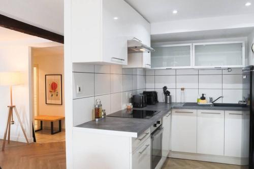 une cuisine avec des armoires blanches et des appareils en acier inoxydable dans l'établissement Le Contemporain, Hypercentre Mulhouse, à Mulhouse